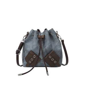 Grey denim and brown leather bucket bag with drawstring closure and slim shoulder strap