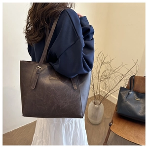 Detail of vintage brown leather tote bag with gold logo and slim shoulder straps