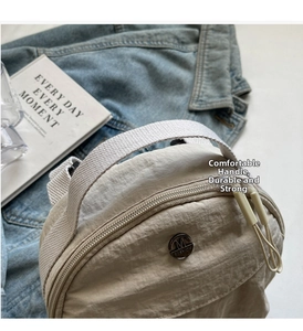 Detail of nylon bag with M FASHION metal logo and rope zippers on beige fabric