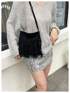 Street style shot of a black bohemian crossbody bag with long decorative fringe tassels