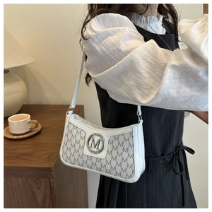 Close-up of white underarm bag featuring all-over M letter pattern and metal logo detail
