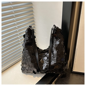Macro detail of large black sequins on shoulder bag with shimmering light effect