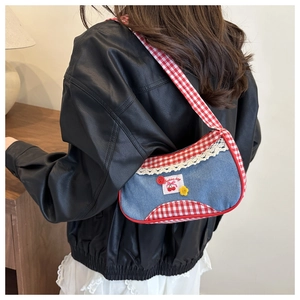 Detail of vintage denim underarm bag with red plaid trim and cherry floral embroidery
