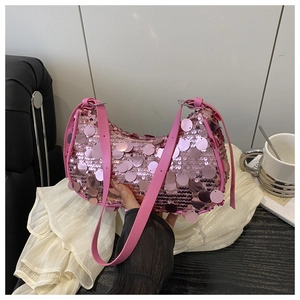 Close-up of pink sequined underarm bag with glossy metallic finish and leather strap