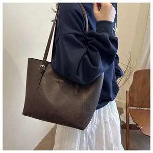 Dettaglio della grande borsa tote in ecopelle marrone scuro con placca in metallo e tracolla