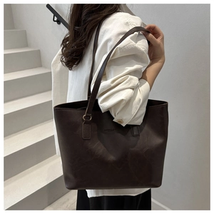 Dark brown retro leather tote bag with long straps worn on shoulder by model