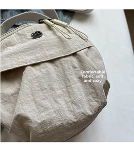 Detailed macro view of the pleated nylon fabric texture and metal logo plate on the bag