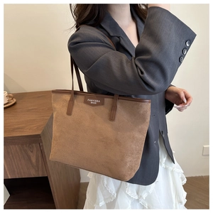 Detail of the suede texture and leather brand patch on the brown tote shoulder bag