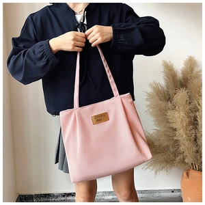 Close-up of pink canvas tote bag showing the textured fabric and leather logo patch