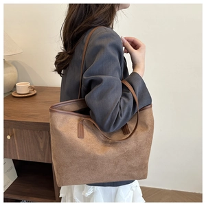 Detail view of large brown suede tote bag with slim leather handles for daily commute