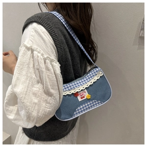 Detail of blue denim shoulder bag with plaid pattern, lace trim and cherry embroidery