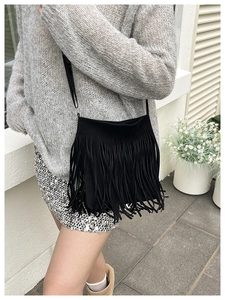 Detail of a black tassel crossbody bag with sleek leather straps for daily styling