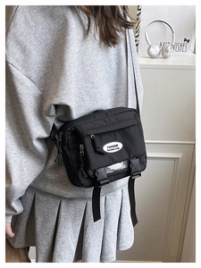 Detail of black nylon messenger bag featuring adjustable strap and buckle closure