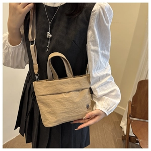 Detailed view of beige crinkle fabric shoulder bag with nylon strap and metal logo