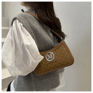 Detail of vintage brown underarm bag with M letter print and silver metal buckle