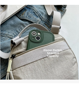 Close-up of the front zipper pocket on a beige nylon crossbody bag showing phone storage