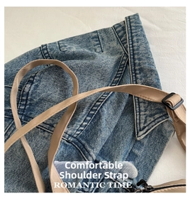 Detail of adjustable camel leather strap with black metal buckle on blue denim bag
