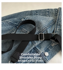 Close-up of adjustable black nylon shoulder strap with silver metal buckle on denim