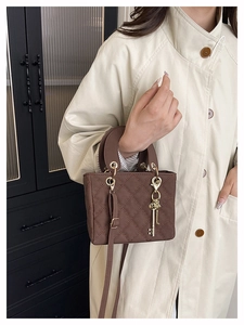 Close-up of brown quilted leather mini bag with golden key charm and arched top handle