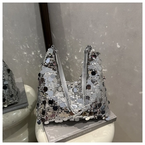 Détail d'un sac à main pailleté argenté étincelant sur un tabouret blanc et chic