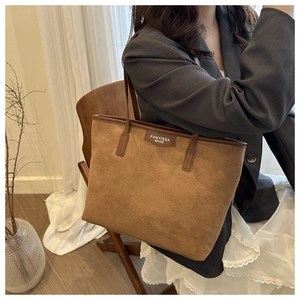 Detailed texture of a brown suede tote bag featuring a brand logo on premium material