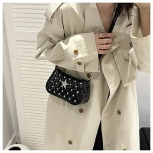 Close-up of black quilted shoulder bag with silver star and rhinestones on a trench coat
