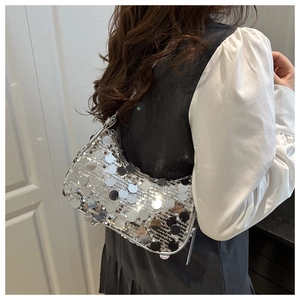 Side view of woman wearing a silver large sequin crescent bag with disco party style