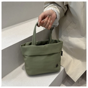 Detail of olive green kids crossbody bag featuring premium textured fabric and metal badge