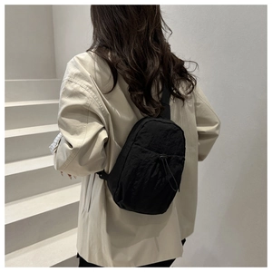 Detail of minimalist black nylon sling bag with drawstring and adjustable strap