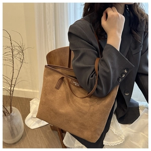 Detailed texture of brown faux suede tote bag featuring slim leather handles and brand tag