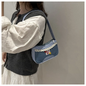 Détail du sac sous le bras en denim avec bordure en dentelle blanche et patch cerise