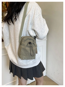 Detail of army green drawstring crossbody bag featuring Duoning white embroidery