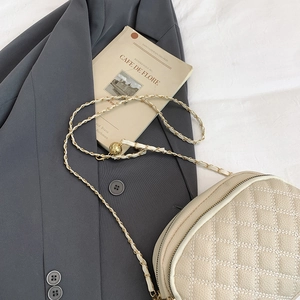 Sac matelassé beige élégant avec chaîne et boule dorée sur un fond de mode chic