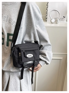 Detail of black crossbody bag featuring multi-pocket design and adjustable nylon strap