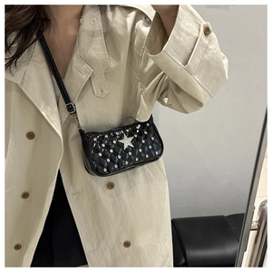 Close-up of black quilted underarm bag with silver studs and crystal star pendant