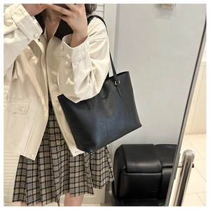 Detail view of large black leather tote bag with thin straps and metallic ring connectors