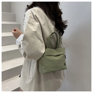 Japanese style sage green nylon tote bag shown in a lifestyle commuter scene on stairs