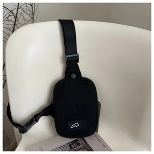 Close-up of black nylon crossbody bag with buckle and logo detail on white chair