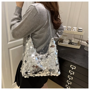 Sac bandoulière pailleté argenté porté par un mannequin dans un cadre moderne