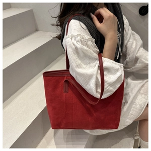 Detail view of large dark red suede tote bag with slim straps worn by a model