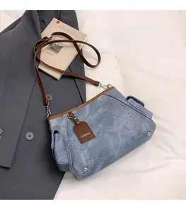 Dettaglio della borsa in tela blu lavata con finiture in pelle marrone e rivetti