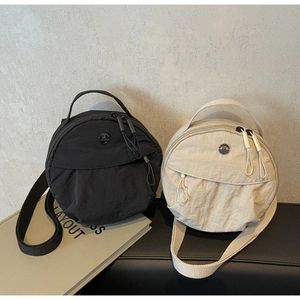 Detail of round nylon crossbody bags in black and beige with metallic M logo and strap
