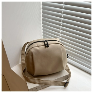 Detail of adjustable strap and dual zippers on a beige crescent nylon crossbody bag