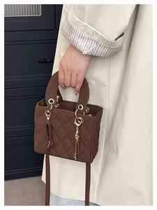 Detailed side view of brown quilted bag with gold hardware and logo key charm