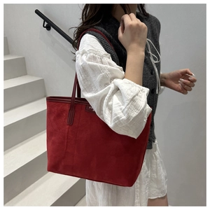 Detail of red matte tote bag with thin straps and small fashion label on gray background