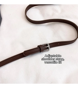 Detail of dark brown adjustable shoulder strap with silver buckle and fine stitching