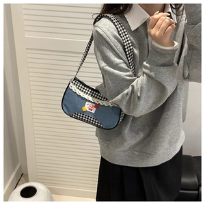 Détail du sac à bandoulière en jean avec patch cerise rouge et bordure en dentelle