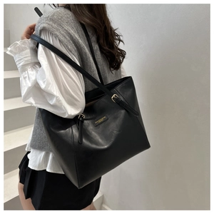 Detail of black leather tote bag with metallic hardware and adjustable shoulder strap