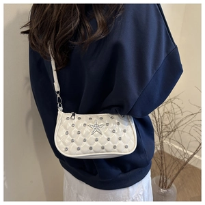 Detailed back view of model wearing white quilted crossbody bag with rhinestone star