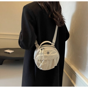 Rear view of a model wearing the round nylon crossbody bag in cream white color
